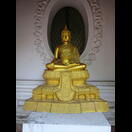 Eine der Buddhafiguren in einer Nische der Außenseite des den Chedi umgebenden Wendelgangs